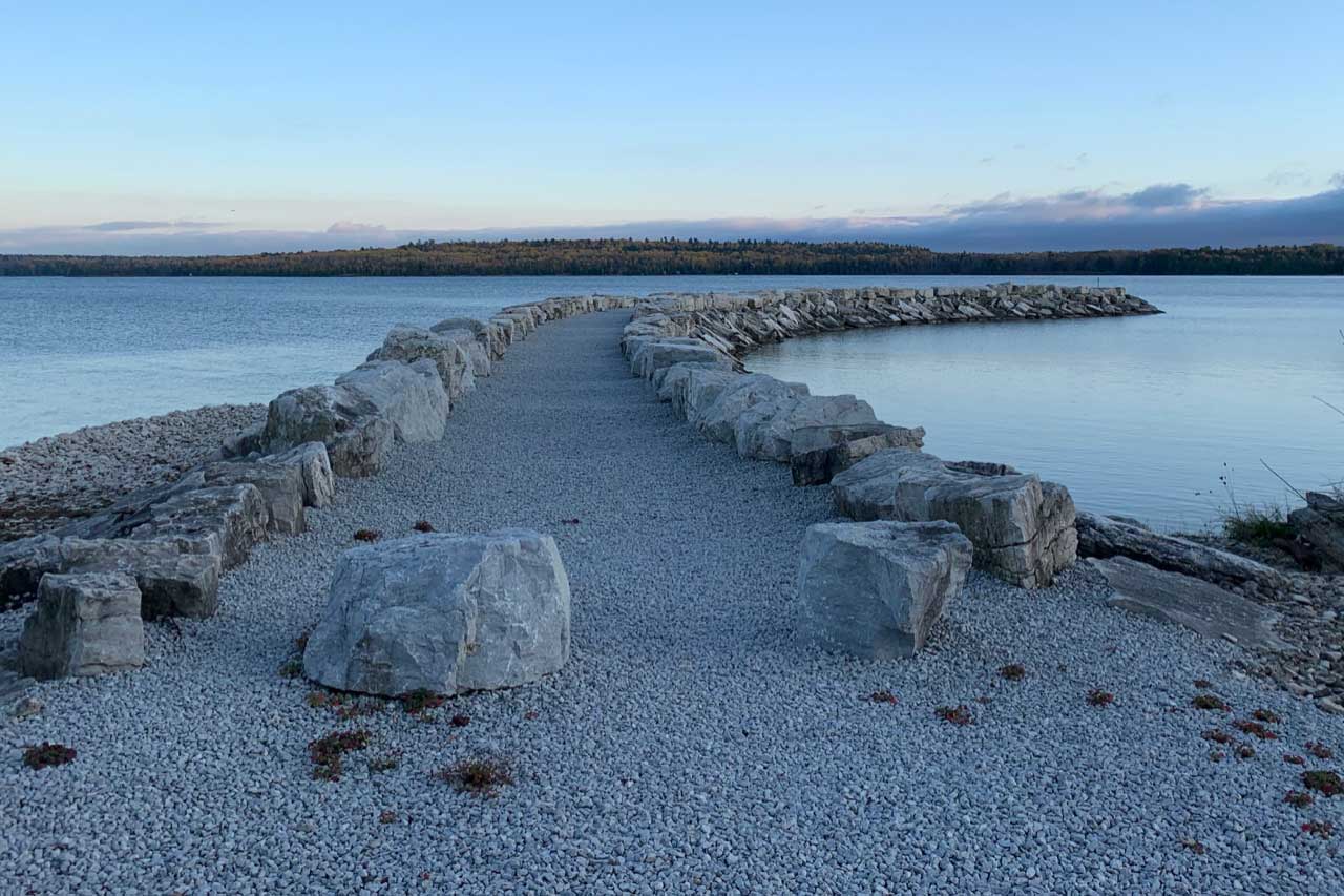 a long stone wall next to a body of water.