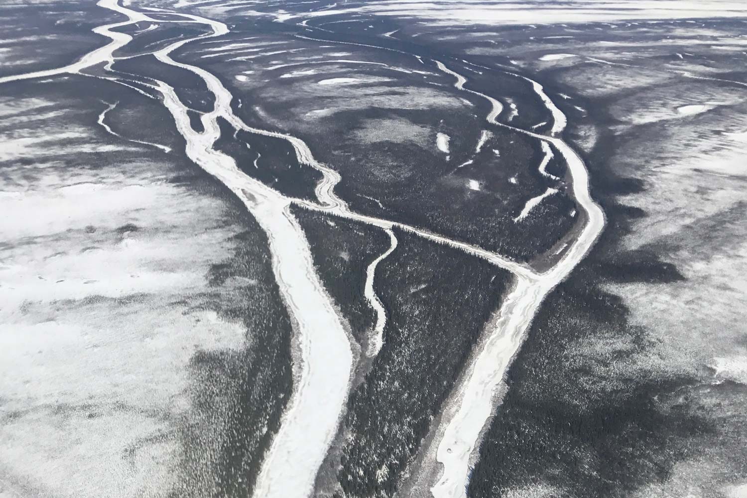 an aerial view of a river in the snow.