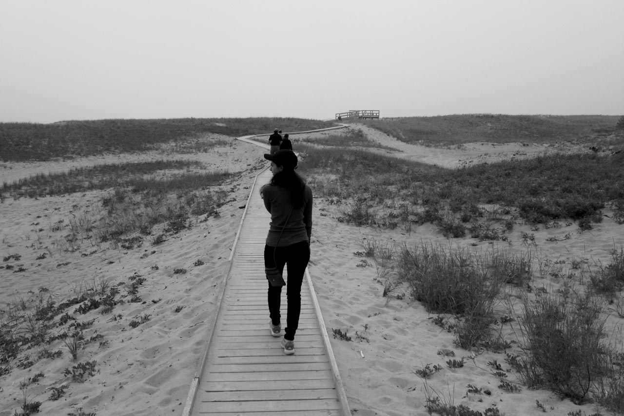 a woman walking down a path in the sand.