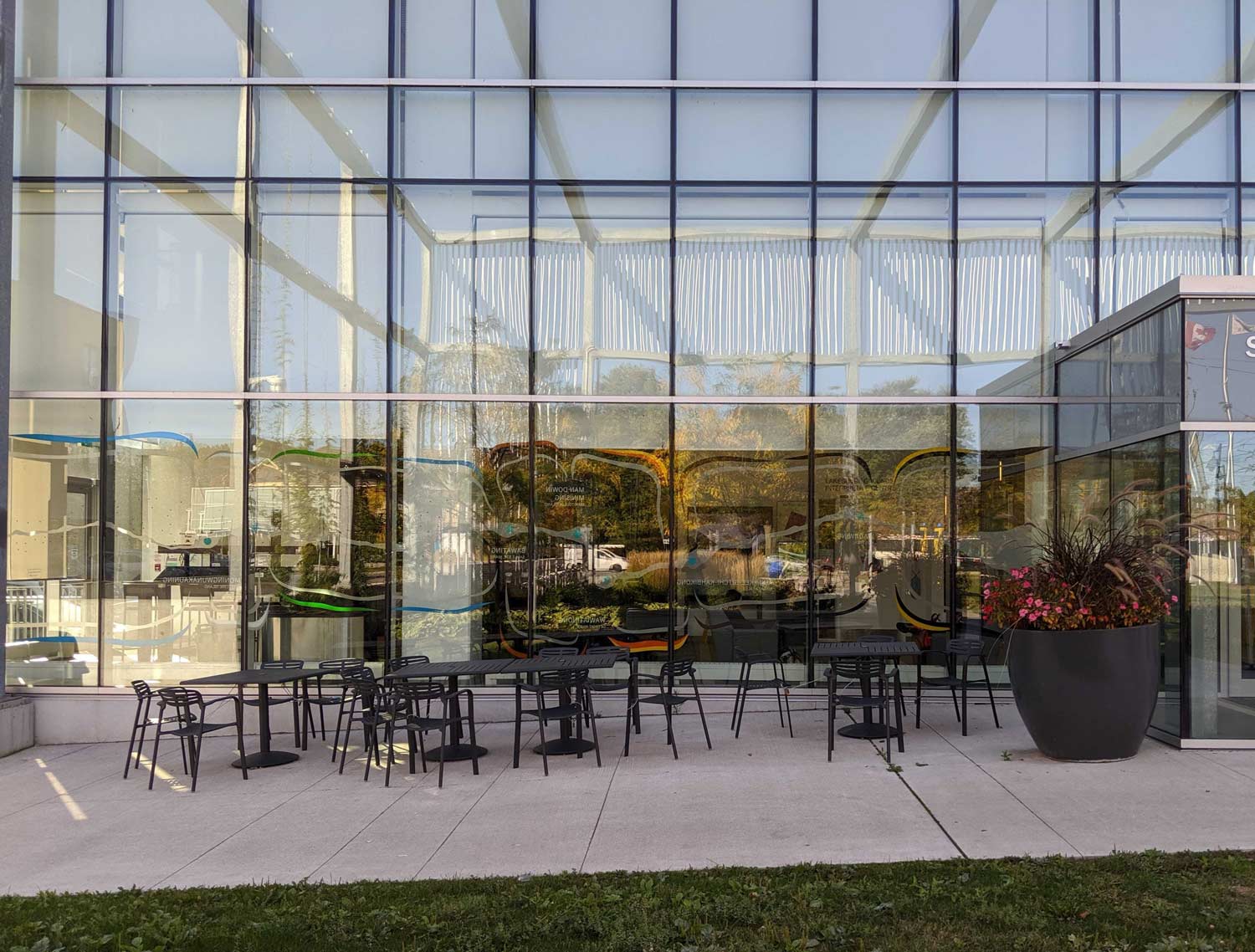 a group of tables and chairs in front of a glass building.